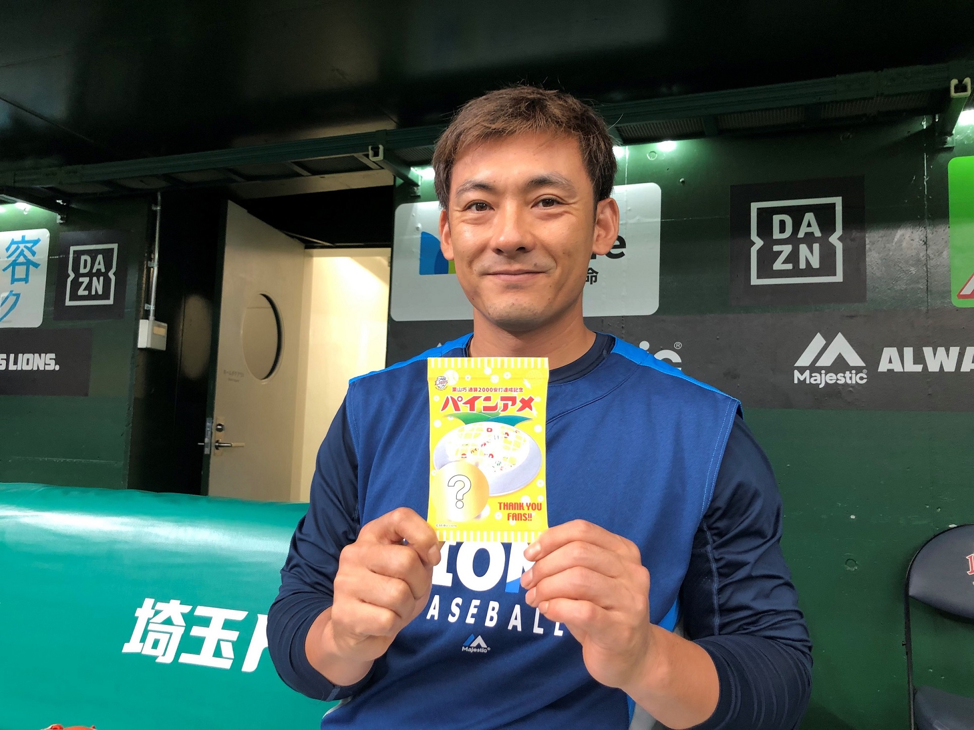 オリジナルパッケージのパインアメ」を手に笑顔の栗山選手